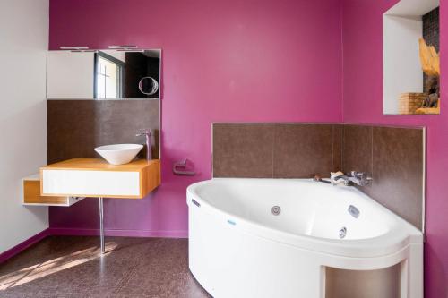 La salle de bains est pourvue d'une baignoire blanche et de murs violets. dans l'établissement Villa climatisée avec vue en pleine pinède aixoise, à Saint-Marc-Jaumegarde
