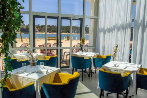 Hôtel du Parc & Spa في هوسيغور: مطعم بطاولات وكراسي مطل على الشاطئ