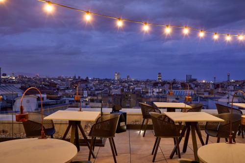 a patio with tables and chairs and a view of a city at InterContinental Barcelona by IHG in Barcelona