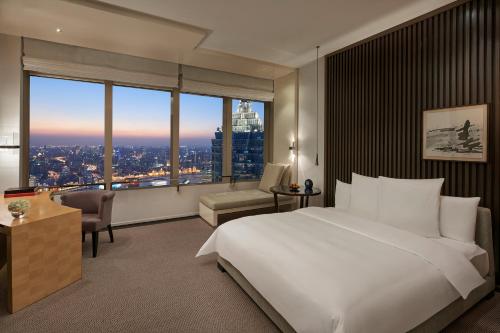 ein Schlafzimmer mit einem großen weißen Bett und einem großen Fenster in der Unterkunft Park Hyatt Shanghai in Shanghai