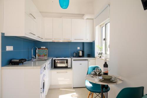 una cucina con armadi bianchi e pareti blu di Artemis apartment first floor a Eloúnda