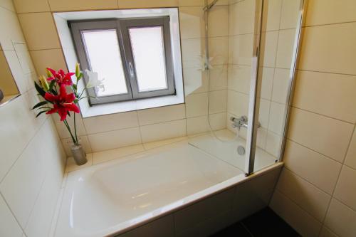 a bathroom with a tub and a window and a vase of flowers at FeWoZauber - Domspatz, 50qm, Top-Lage, Style, Dachterrasse, Business in Schwerin