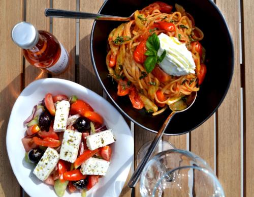 a table with a bowl of pasta and a plate of food at IADES suites in Afitos