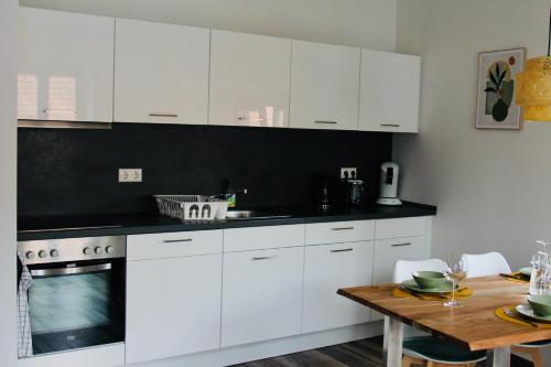 a kitchen with white cabinets and a wooden table at FeWoZauber - Domspatz, 50qm, Top-Lage, Style, Dachterrasse, Business in Schwerin