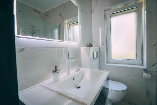 a white bathroom with a sink and a toilet at LUMIN 4 in Senj