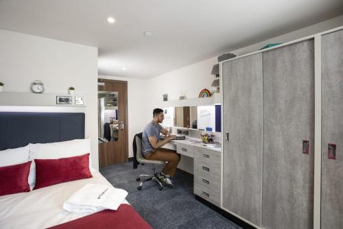 a man sitting in a chair at a desk in a bedroom at For Students Only Ensuite Bedrooms with Shared Kitchen at Reynard House located in Leicester in Leicester