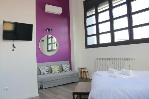 1 dormitorio con paredes moradas, 1 cama y 1 sofá en Smart and Comfy Apartment - Via Repubblica di San Marino, en Milán