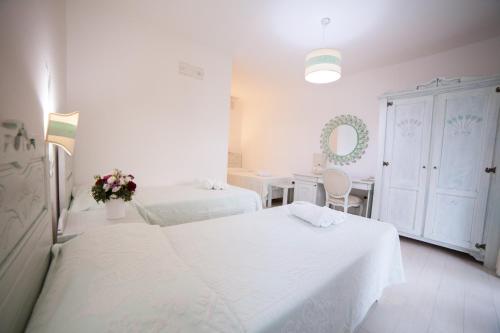a white room with two beds and a table at Hotel Golden Gate in Bortigiadas