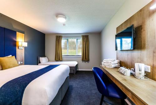 Habitación de hotel con 2 camas, escritorio y TV. en Days Inn Hotel Gretna Green en Gretna Green