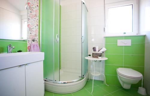 a green bathroom with a toilet and a shower at Apartments Medvid in Trogir