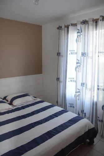 - une chambre dotée d'un lit avec des rideaux bleus et blancs dans l'établissement Spacieux T2 Gd confort jardin et garage privatifs, à La Rochelle