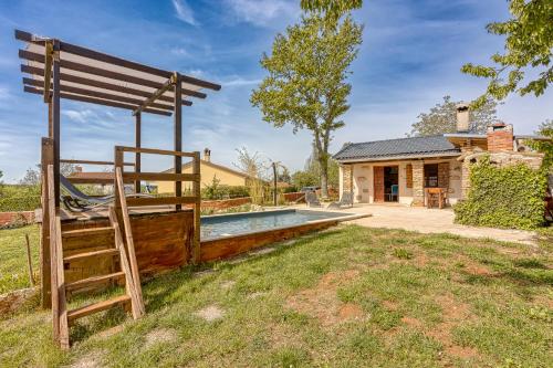 een achtertuin met een zwembad en een schommel en een huis bij Rustic Home Izabel - Happy Rentals in Pazin