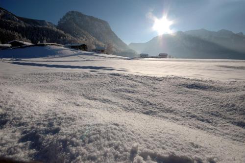 a snow covered field with the sun in the background at Landhotel Binderhäusl Garni in Inzell
