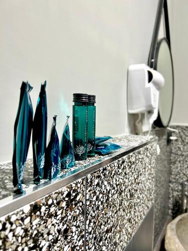 a counter with four blue glass vases on it at Favola Guesthouse Affittacamere in Nettuno