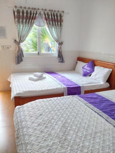 2 Betten in einem Zimmer mit Fenster in der Unterkunft Lavender Sa Huỳnh Hotel Quốc Lộ 1A in La Vân (2)