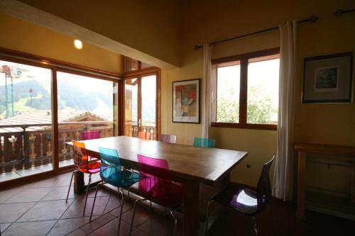 une salle à manger avec une table en bois et des chaises colorées dans l'établissement Chalet The Loft, aux Gets