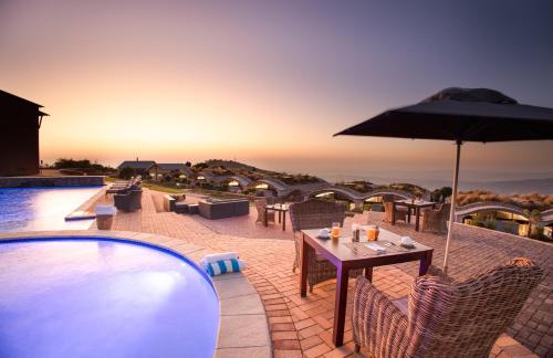 a patio with a table and umbrella next to a pool at Angels View Hotel in Graskop