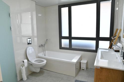 a bathroom with a tub and a toilet and a sink at Casa Cohen C Kineret קאסה כהן סי כנרת in Migdal