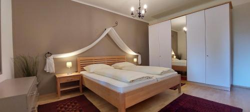 1 dormitorio con 1 cama grande y espejo en Appartements Romanin, en Pörtschach am Wörthersee