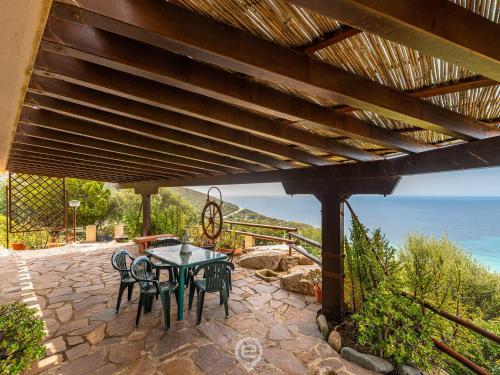 un patio con mesa y sillas bajo una pérgola en Enchanting Seaview Getaway, en Torre delle Stelle