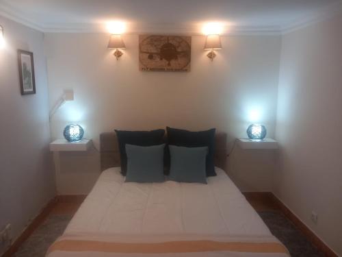 a bed in a room with two lights on the wall at Villa Casa das Palmeiras in Charneca