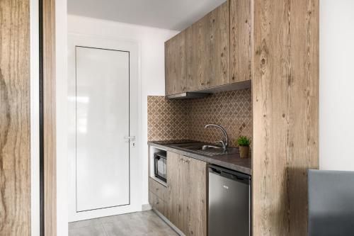 a kitchen with wooden cabinets and a sink at Delight Corfu Apart Hotel, Sidari in Sidari