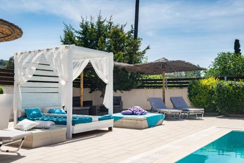 a patio with a bed and chairs next to a pool at Delight Corfu Apart Hotel, Sidari in Sidari