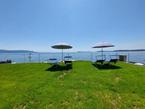 two tables and two chairs with umbrellas on a lawn at Pizzocolo resort fasano in Gardone Riviera