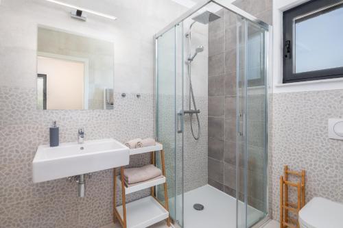 La salle de bains est pourvue d'un lavabo et d'une douche en verre. dans l'établissement Sun Resort Apartments, à Zečevo