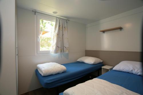 mały pokój z 2 łóżkami i oknem w obiekcie Camping Adria Mobile Home Park Umag w mieście Umag