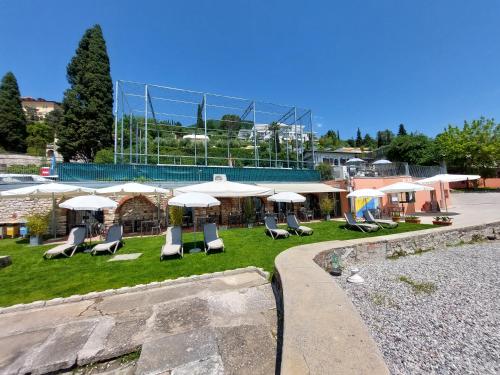 un grupo de sillas y sombrillas frente a un edificio en Pizzocolo resort fasano, en Gardone Riviera