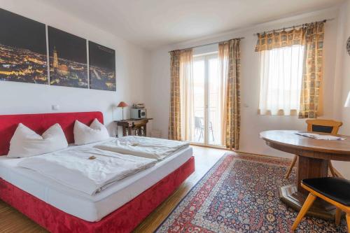 Schlafzimmer mit einem roten Bett und einem Tisch in der Unterkunft Hotel Freischütz in Landshut