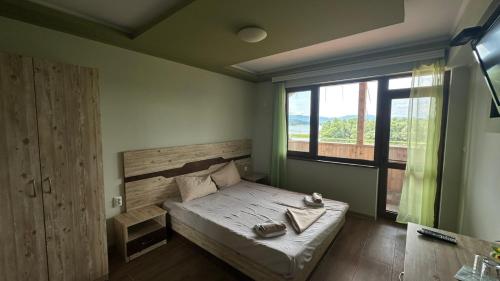 a bedroom with a bed and a large window at ВАЛ -МАЦА-7- яз Жребчево in Tvŭrditsa
