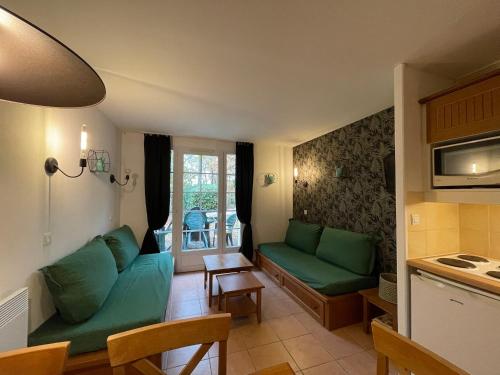 uma sala de estar com sofás verdes e uma cozinha em Appartement dans joli village de vacances 47150 em Monflanquin