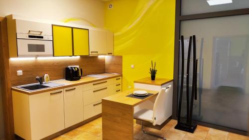 a yellow kitchen with a sink and a refrigerator at Apartmány Dačice in Dačice