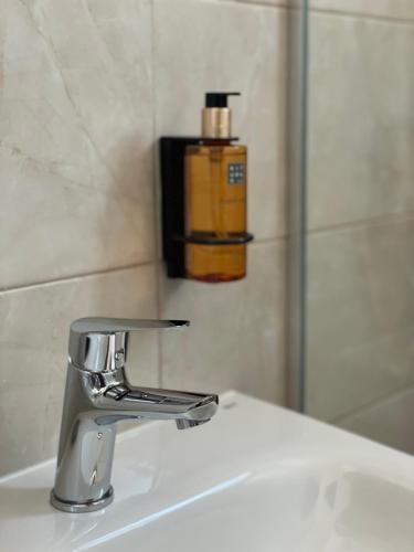a bathroom sink with a faucet and a bottle of soap at Morpheus apartmani in Sremska Mitrovica