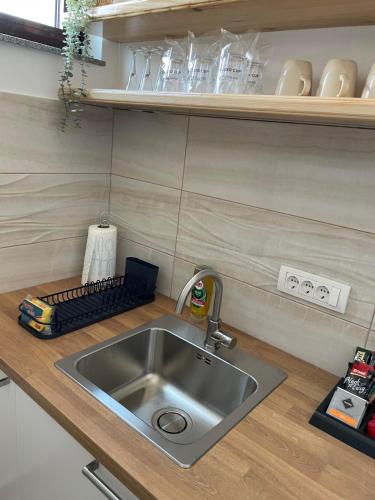 a kitchen counter with a stainless steel sink and shelves at Morpheus apartmani in Sremska Mitrovica