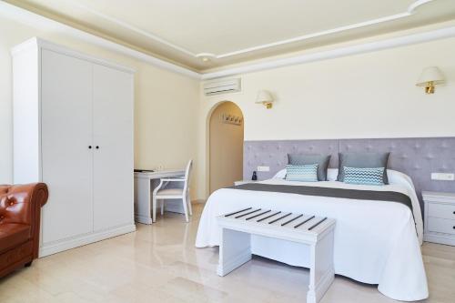 a white bedroom with a large bed and a table at Grand Hotel Palladium Santa Eulalia del Río in Santa Eularia des Riu