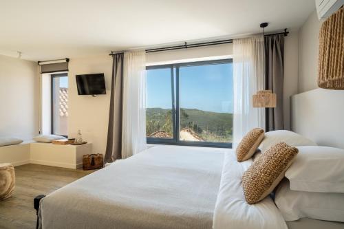 a bedroom with a large bed with a large window at Casa da Ursa in Colares