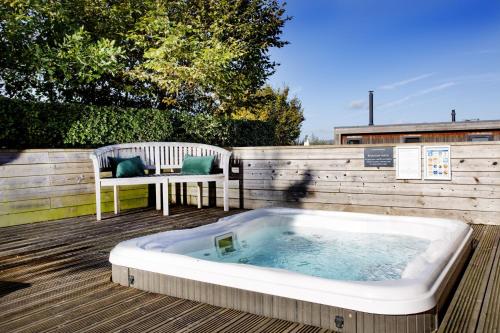 a hot tub on a wooden deck with a bench at The Sleights, Strawberryfield Park - Hot Tub - Free WiFi & Parking - Pets Allowed 2 in Cheddar