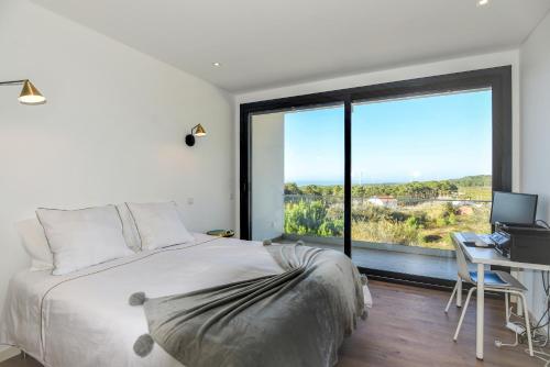 a bedroom with a bed and a desk and a window at Moradia Sussurros do Mar in Nazaré