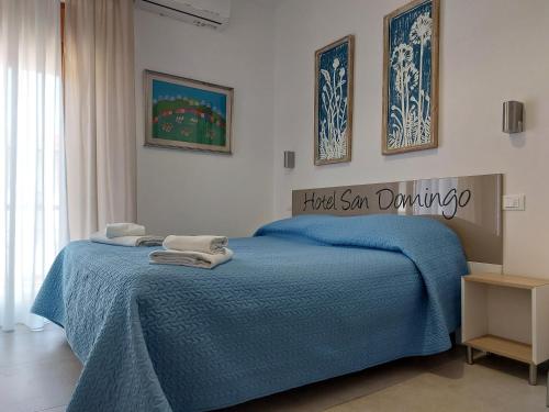 Hotel San Domingo في ليدو دي كامايوري: غرفة نوم مع سرير وبطانية زرقاء