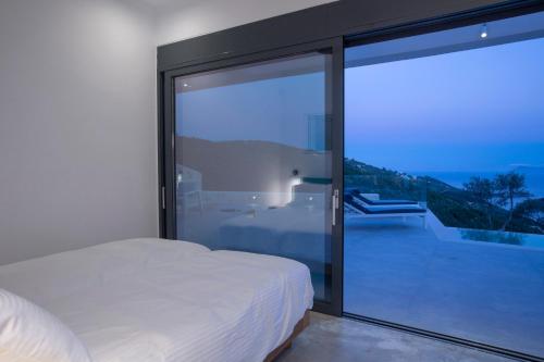 a bedroom with a bed and a large glass window at Villa Rona Lefkada in Sivota