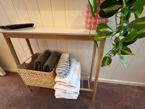 a basket under a table with towels and a plant at Rødseth gårdsovernatting Dobbeltrom in Molde