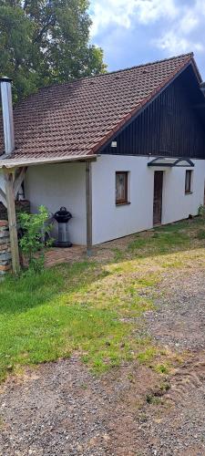 a white house with a black roof and a yard at Domek u rybníka in Schloss Bösig
