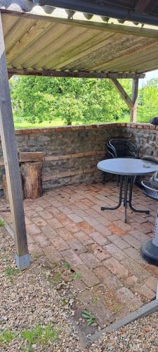 a patio with a table and a bench under a pavilion at Domek u rybníka in Schloss Bösig