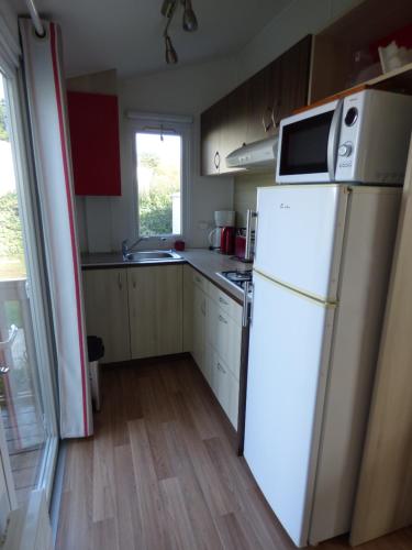 a kitchen with a white refrigerator and a window at Mobil home dans camping 5 étoiles in Bretignolles-sur-Mer