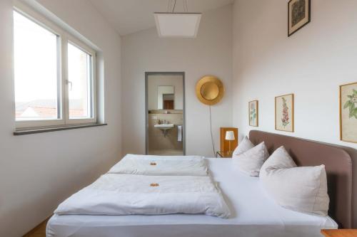 a bedroom with a bed with white sheets and a window at Hotel Freischütz Apartments in Landshut