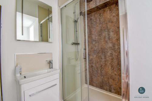a bathroom with a shower and a sink and a mirror at Bowleaze Hideaway - beachside dog friendly in Weymouth