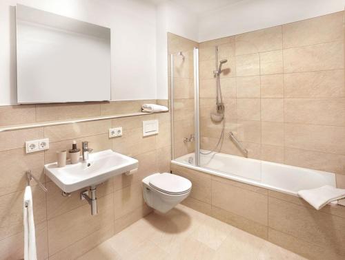 a bathroom with a toilet and a sink and a shower at Hotel Freischütz Apartments in Landshut